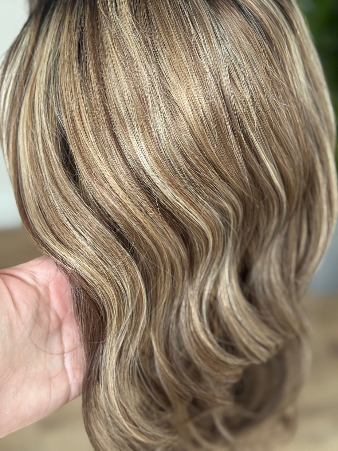 Close up of blonde highlights blended through a dimensional brown human hair wig